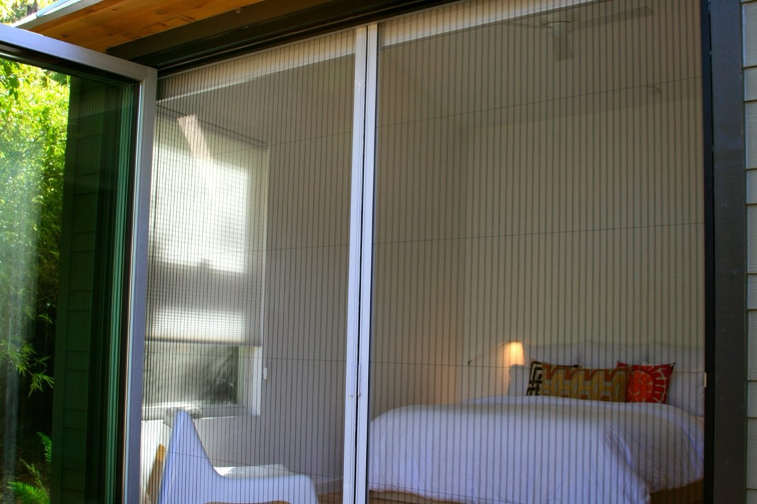 Bedroom with a full wall of glass covered by a pleated screen
