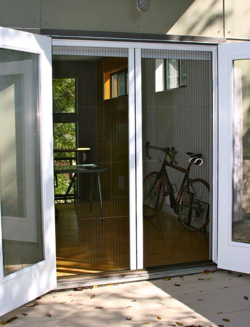 French doors standing open with the pleated screens retracted against the frames