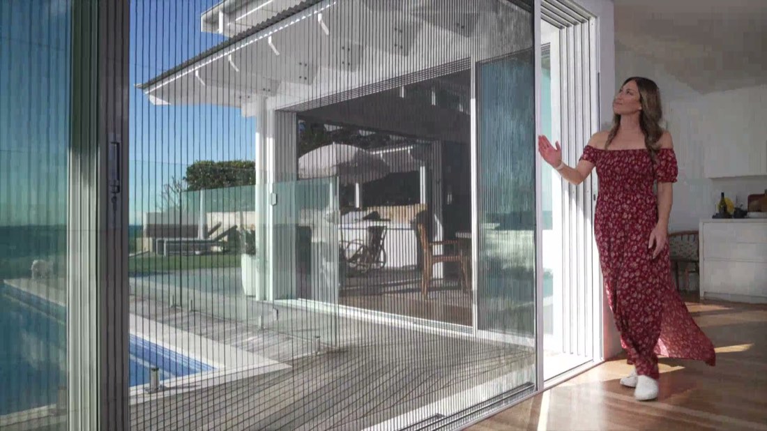 Living room seen through a closed pleated screen, pool and sea beyond