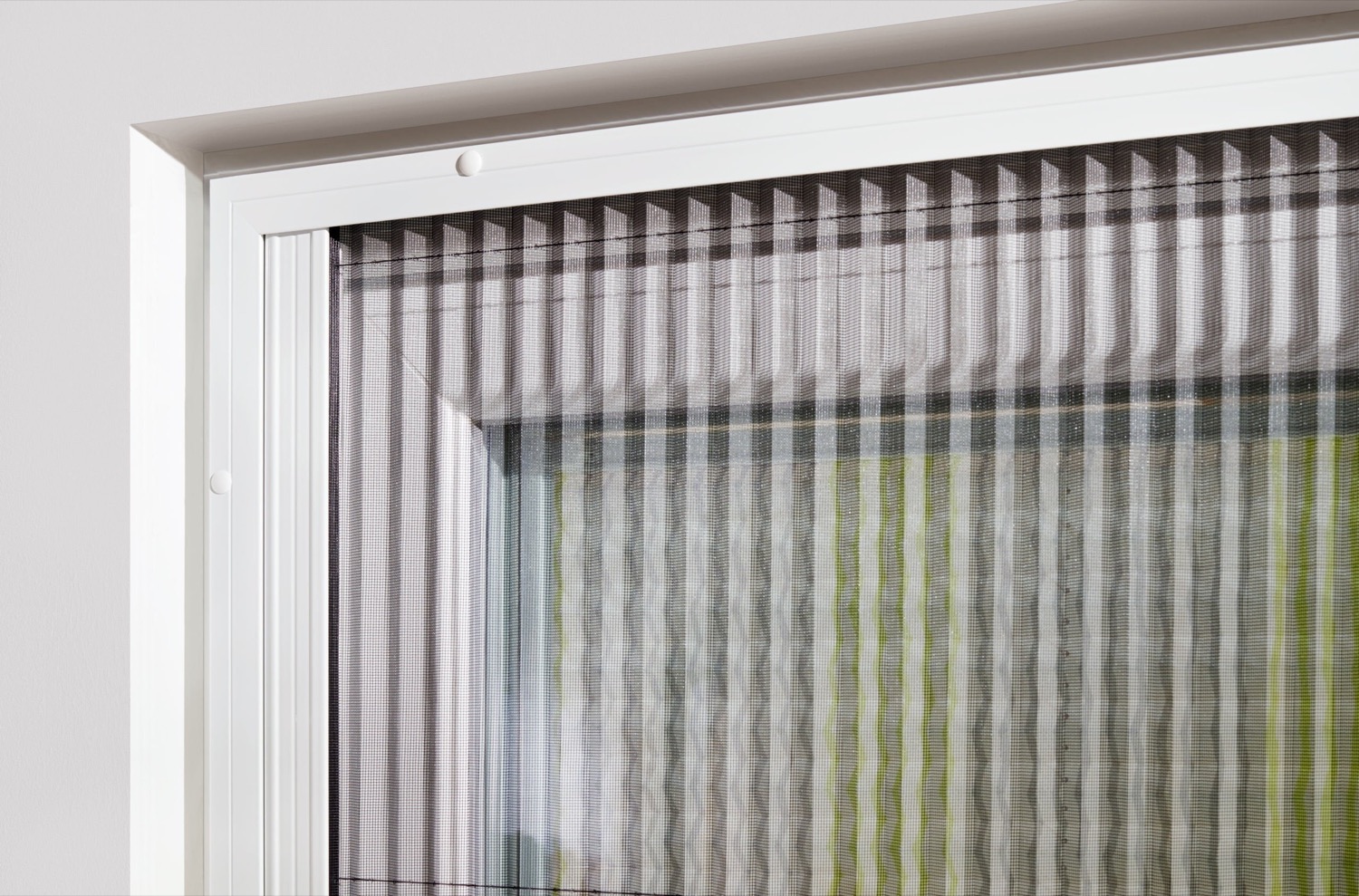 Pleated screen fitted to a white window, drawn most of the way across